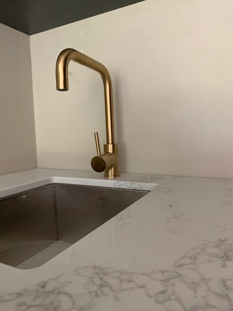 Brushed brass kitchen mixer installed over a new undermount sink